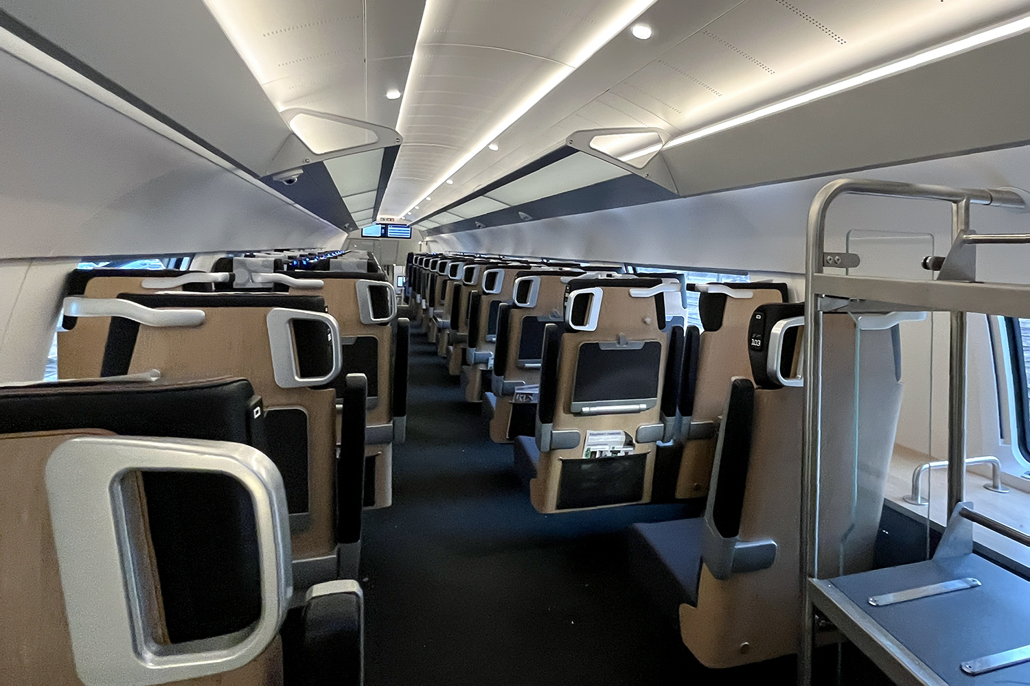 A modern commuter train includes laptop tables and a high-quality interior